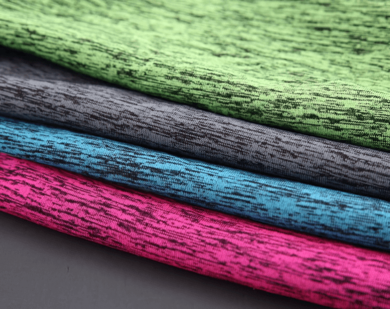 Colorful stack of breathable, quick-dry fabric used in women's sportswear t-shirts, featuring green, gray, blue, and pink options.